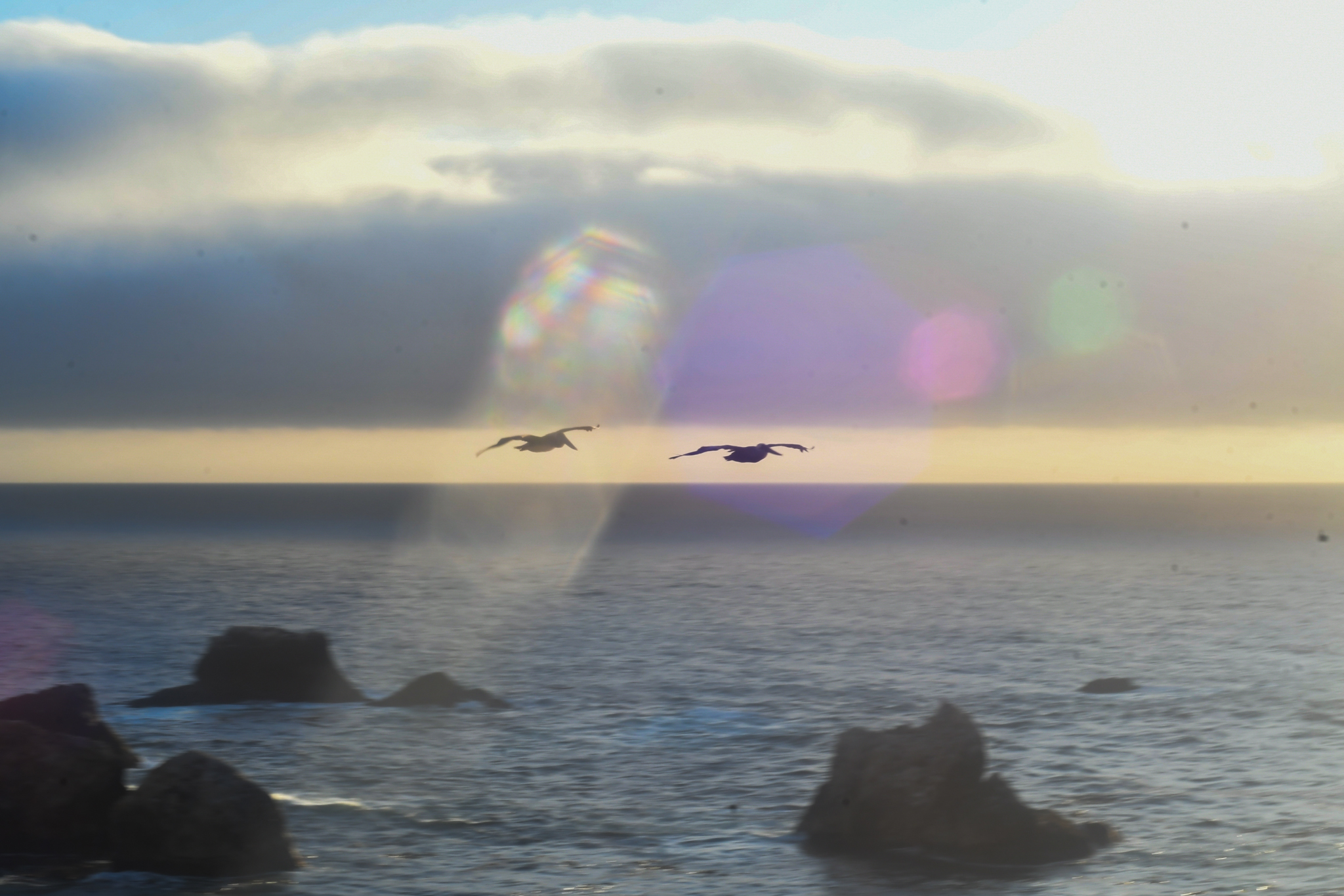 Rock formations sit offshore beneath a pale band of ocean haze.
