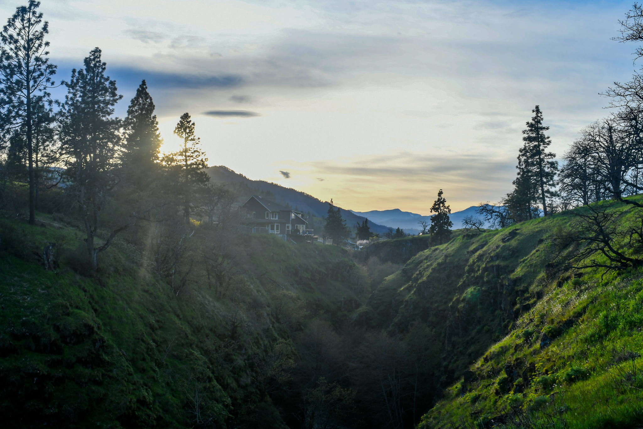 A lone walker crosses a mountain overlook as sunlight breaks through cloud.
